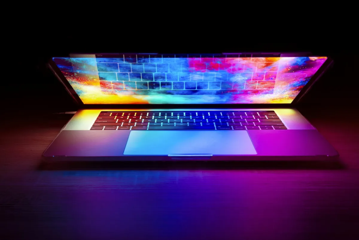 Open laptop with a brightly coloured screen on a dark desk