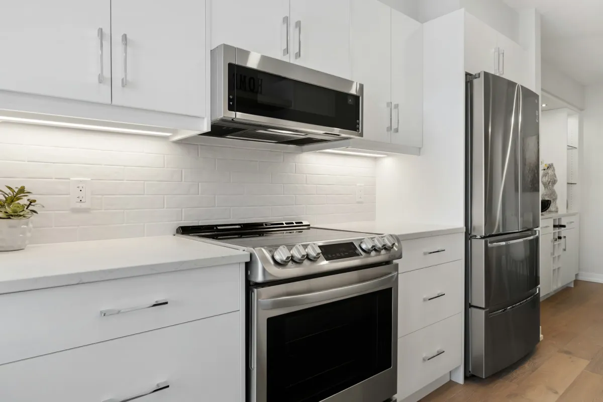 A bright white kitchen with a stainless steel cooker and microwave A bright white kitchen with a stainless steel cooker and microwave