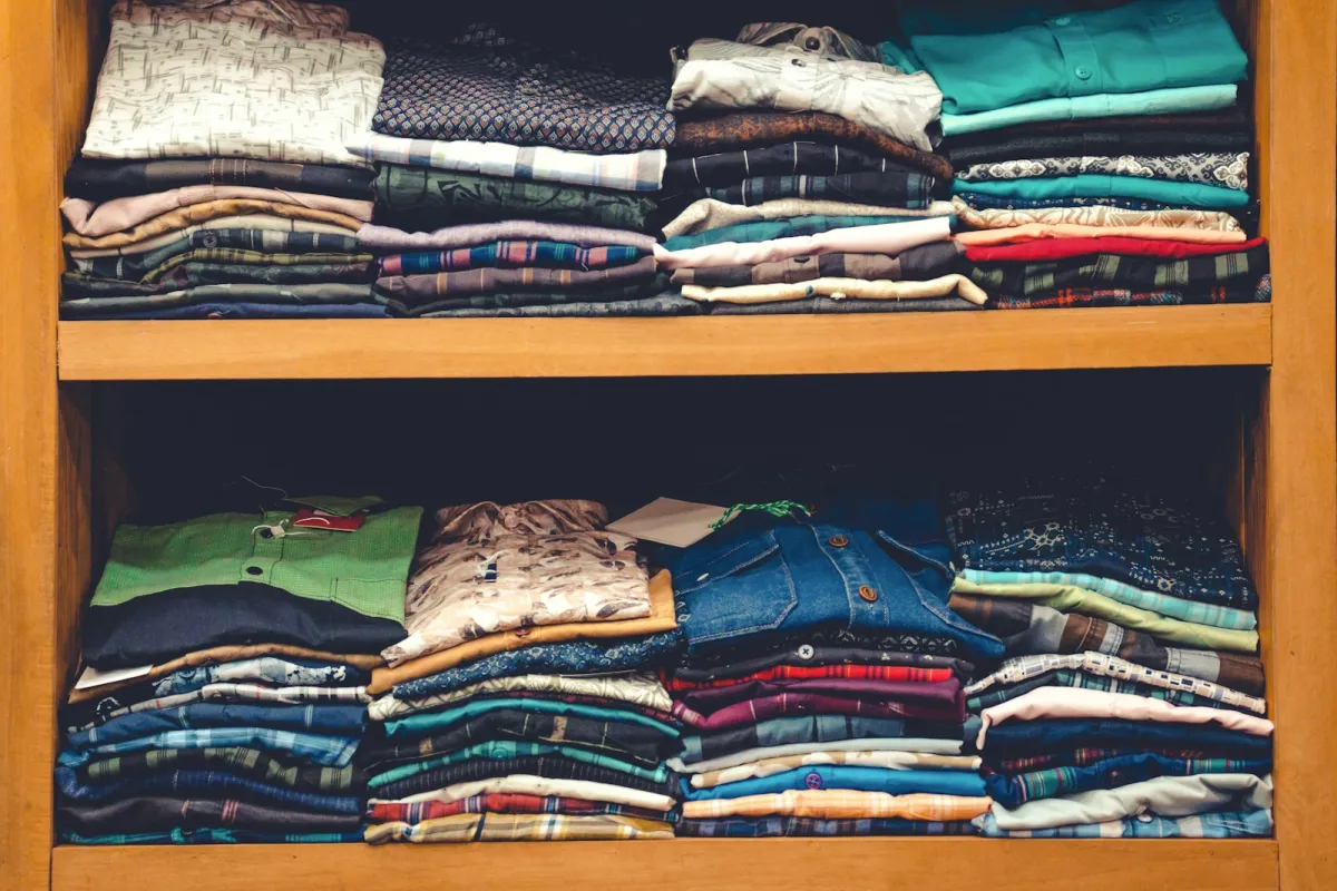 Neat stacks of folded shirts on wooden shelves