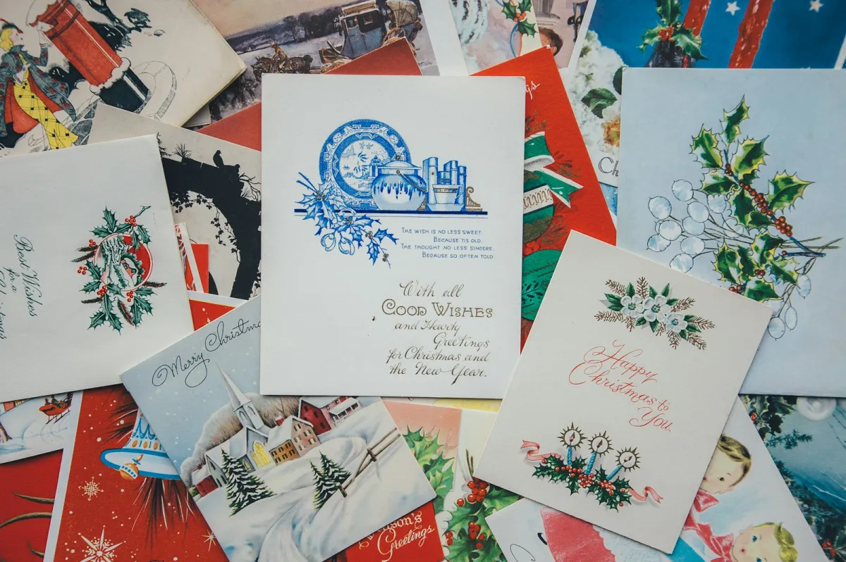 A pile of colourful vintage Christmas and greeting cards spread across a table