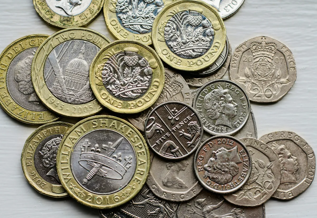 A pile of British pound and pence coins on a table A pile of British pound and pence coins on a table
