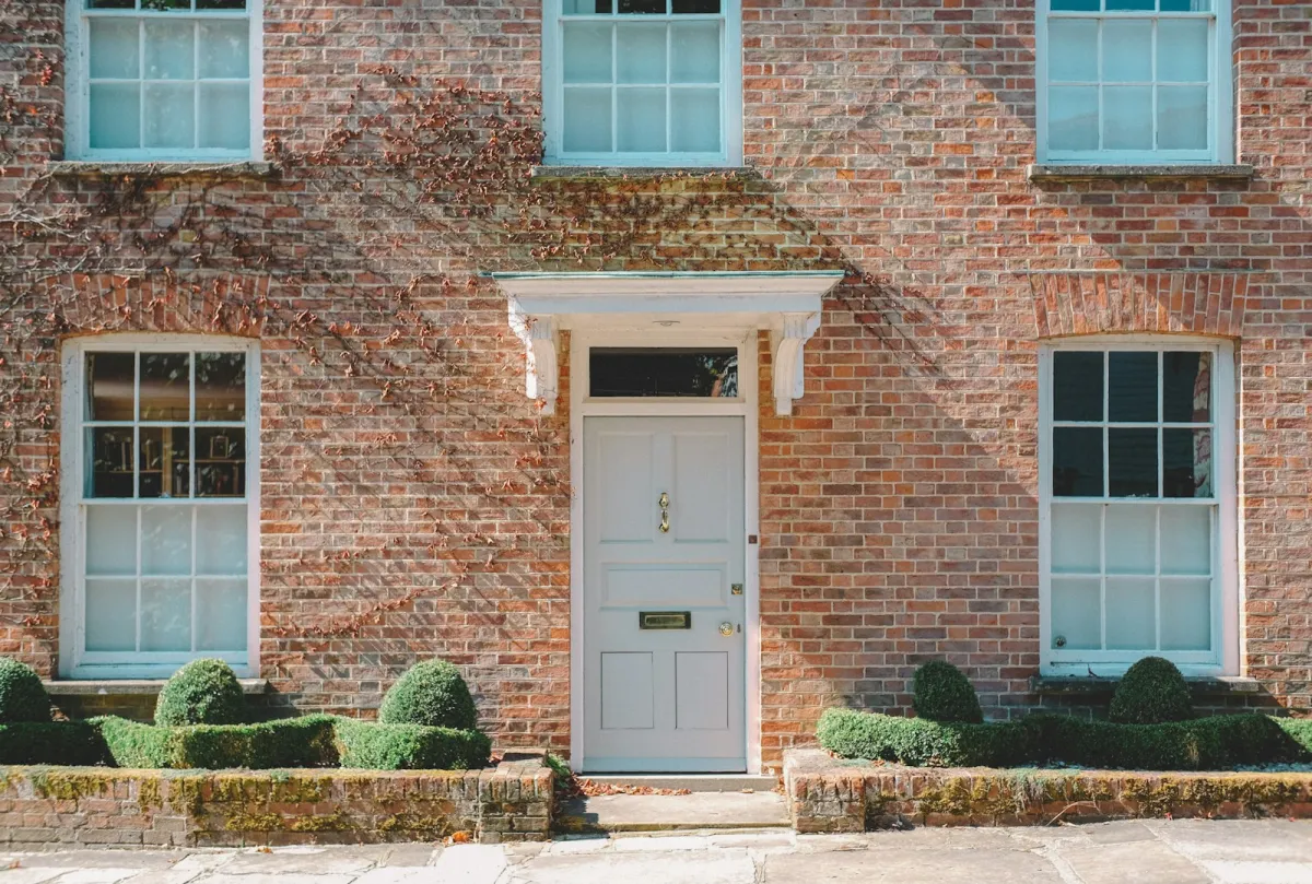 A white front door on a red-brick house with box hedges A white front door on a red-brick house with box hedges