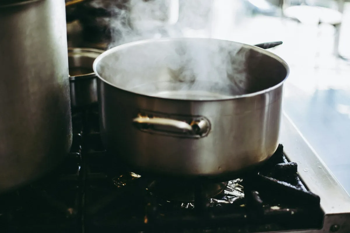 A stainless steel pot steaming on a gas hob A stainless steel pot steaming on a gas hob