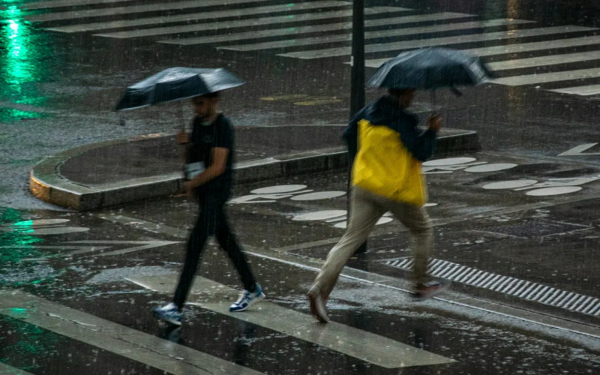 Two people crossing a wet street in heavy rain Two people crossing a wet street in heavy rain