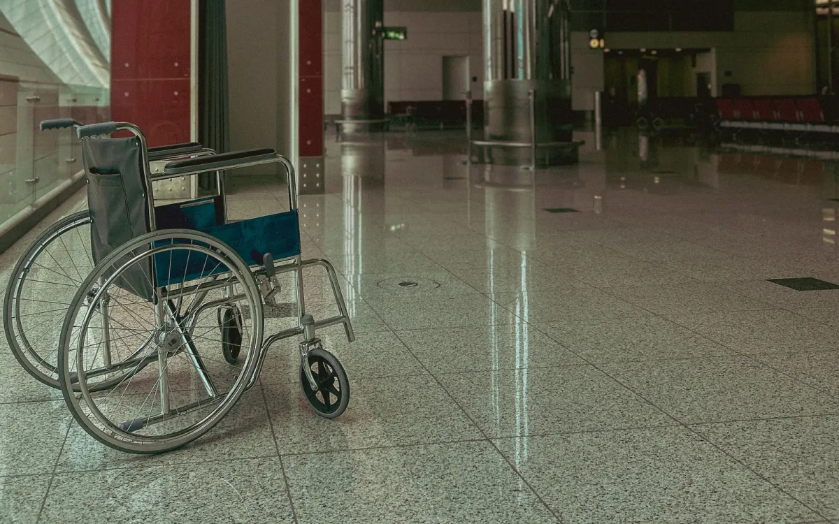 An empty wheelchair on the polished floor of a quiet airport terminal