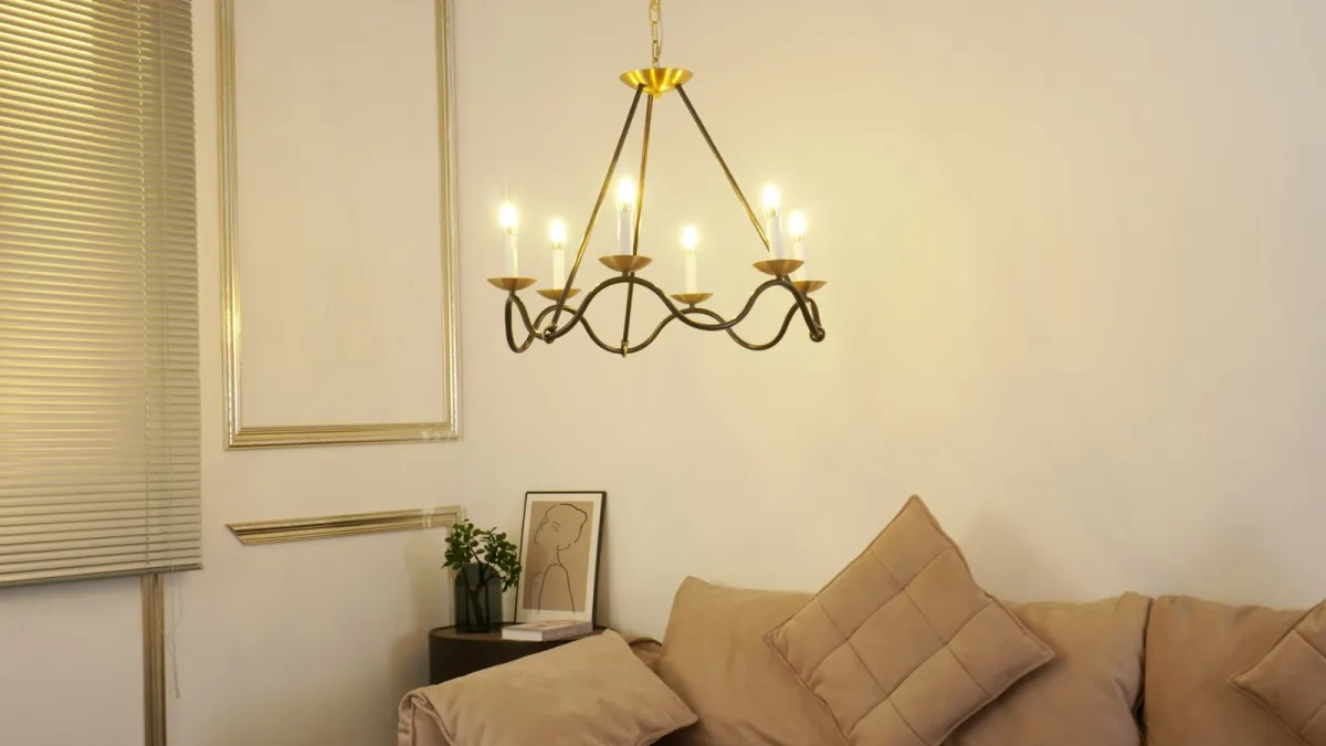 Brass candle-style chandelier hanging above a velvet sofa in a living room