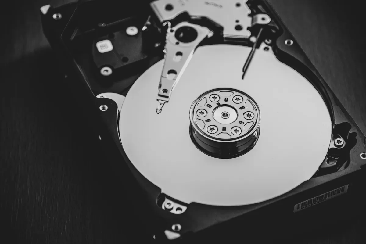 An opened hard disk drive showing its platter and read arm, in black and white
