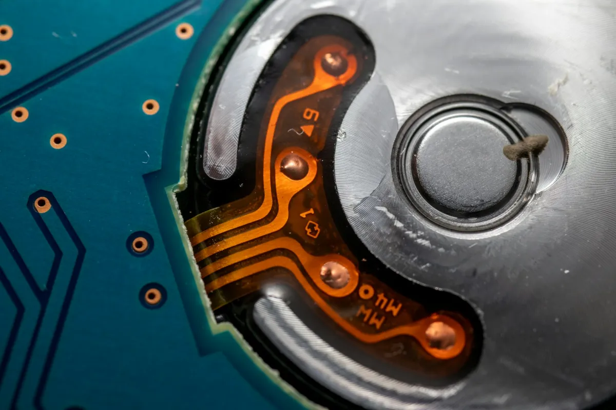 Close-up of the underside of a hard disk drive showing copper contacts and a circuit board