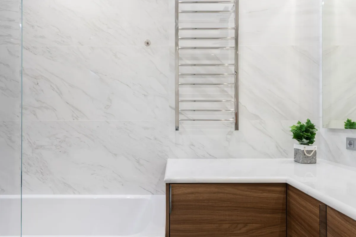 Bright modern bathroom with marble-effect tiles, heated towel rail and wooden vanity Bright modern bathroom with marble-effect tiles, heated towel rail and wooden vanity