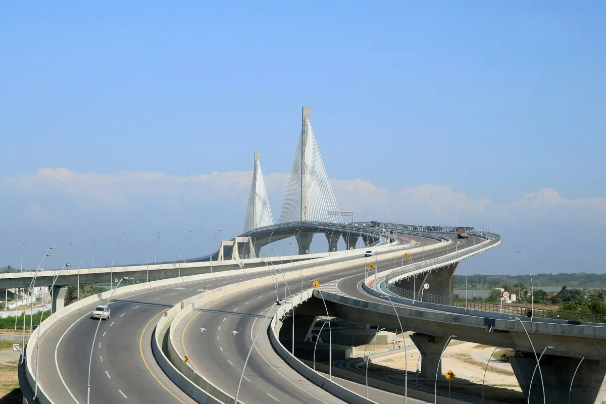 The white cable-stayed Pumarejo bridge and curving approach roads in Barranquilla under a blue sky The white cable-stayed Pumarejo bridge and curving approach roads in Barranquilla under a blue sky