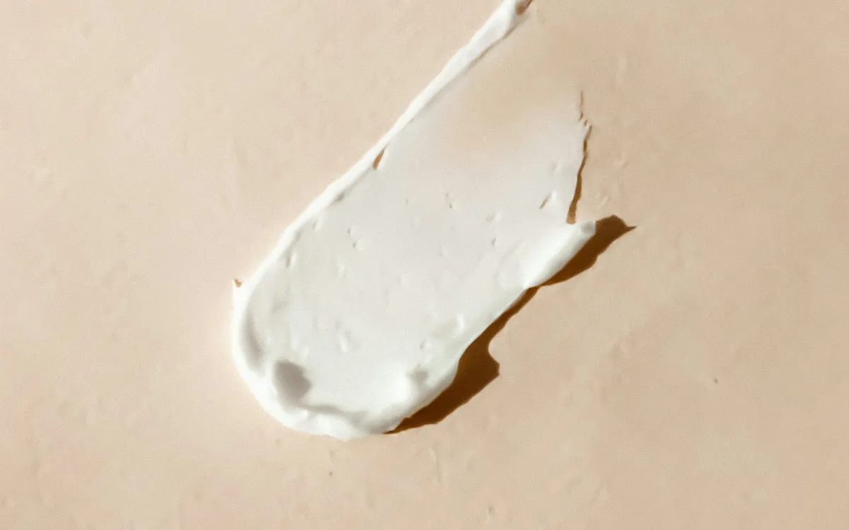A smear of white cream on a soft beige surface A smear of white cream on a soft beige surface