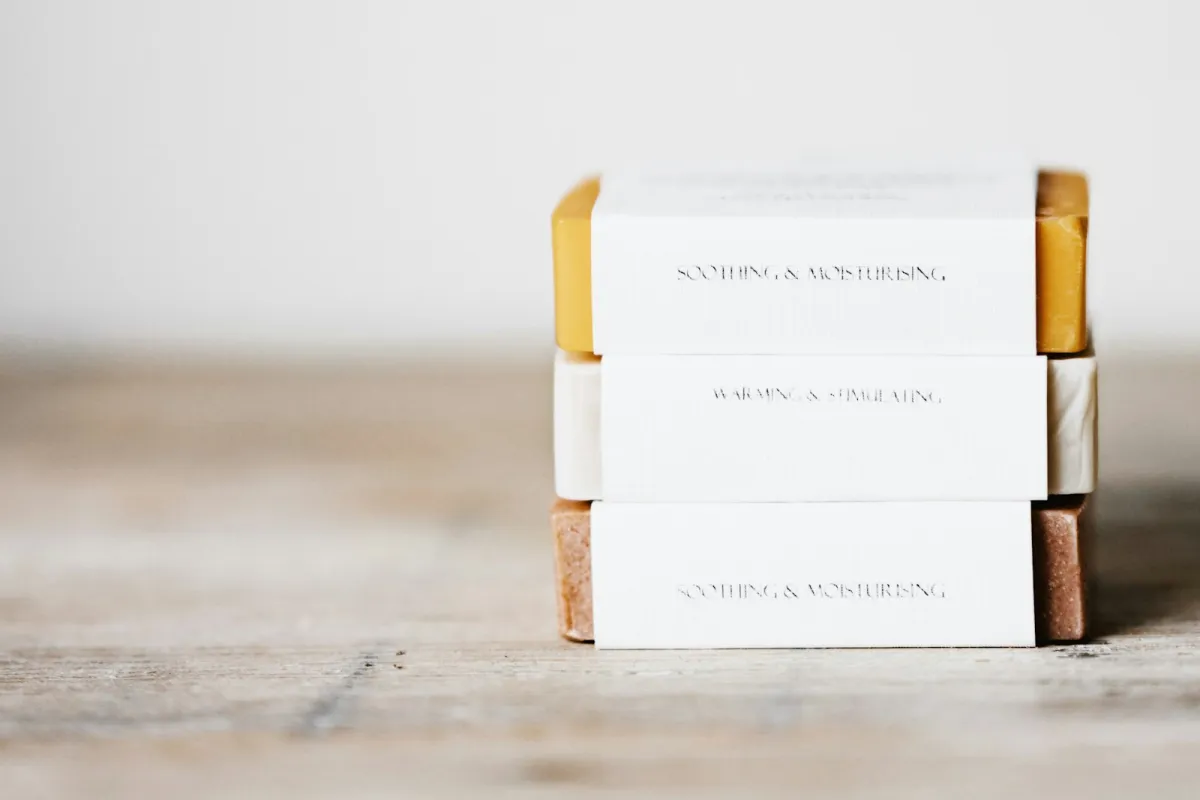 A stack of three handmade soap bars wrapped in plain paper bands on a wooden table