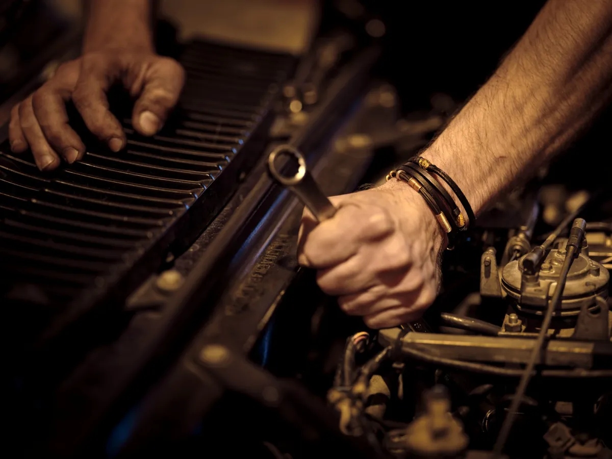 Hands holding a spanner while working on a car engine Hands holding a spanner while working on a car engine