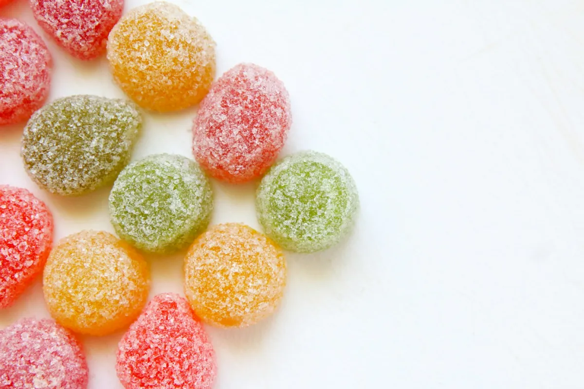 Sugar-coated fruit jelly sweets in red, orange and green on a white table