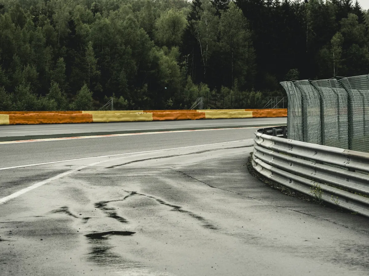 An empty motor racing circuit corner with barriers and trees