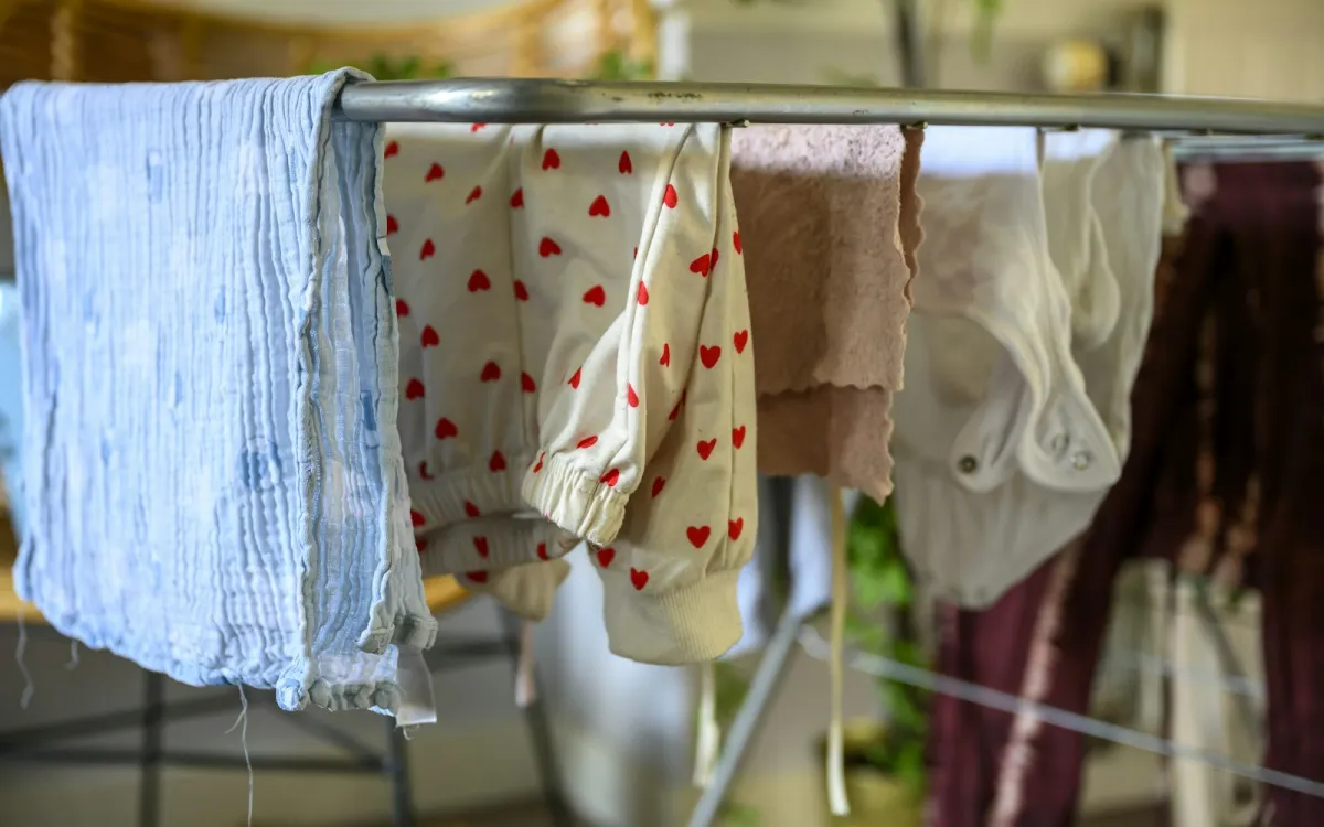 Washing hung over the rail of a metal clothes airer indoors