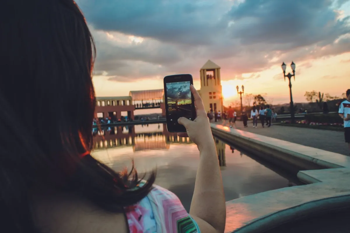 Woman taking a photo of a sunset on her smartphone while sightseeing