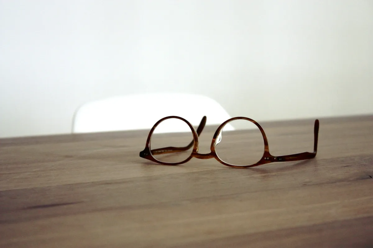 A pair of brown-framed glasses resting on a wooden table