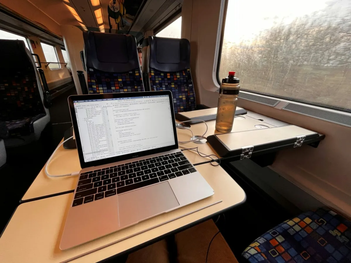 A laptop and water bottle on a fold-down table by a train window A laptop and water bottle on a fold-down table by a train window