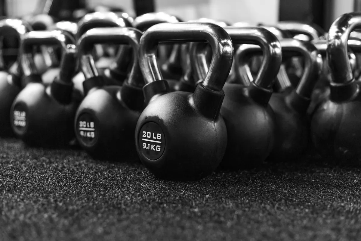 Black and white photo of rows of kettlebells on a gym floor