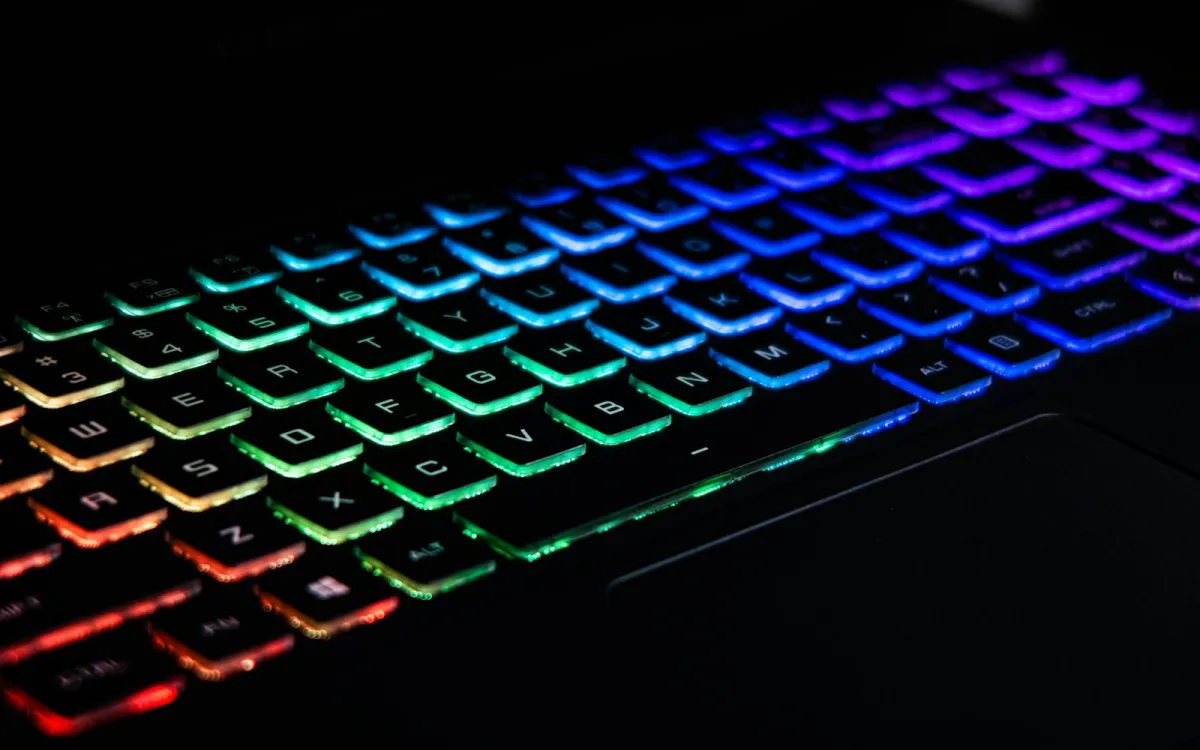 Close-up of a backlit gaming keyboard glowing in rainbow colours Close-up of a backlit gaming keyboard glowing in rainbow colours