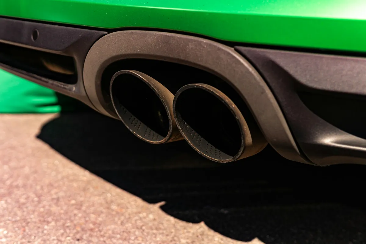 Close-up of twin exhaust tips under the rear bumper of a green car Close-up of twin exhaust tips under the rear bumper of a green car
