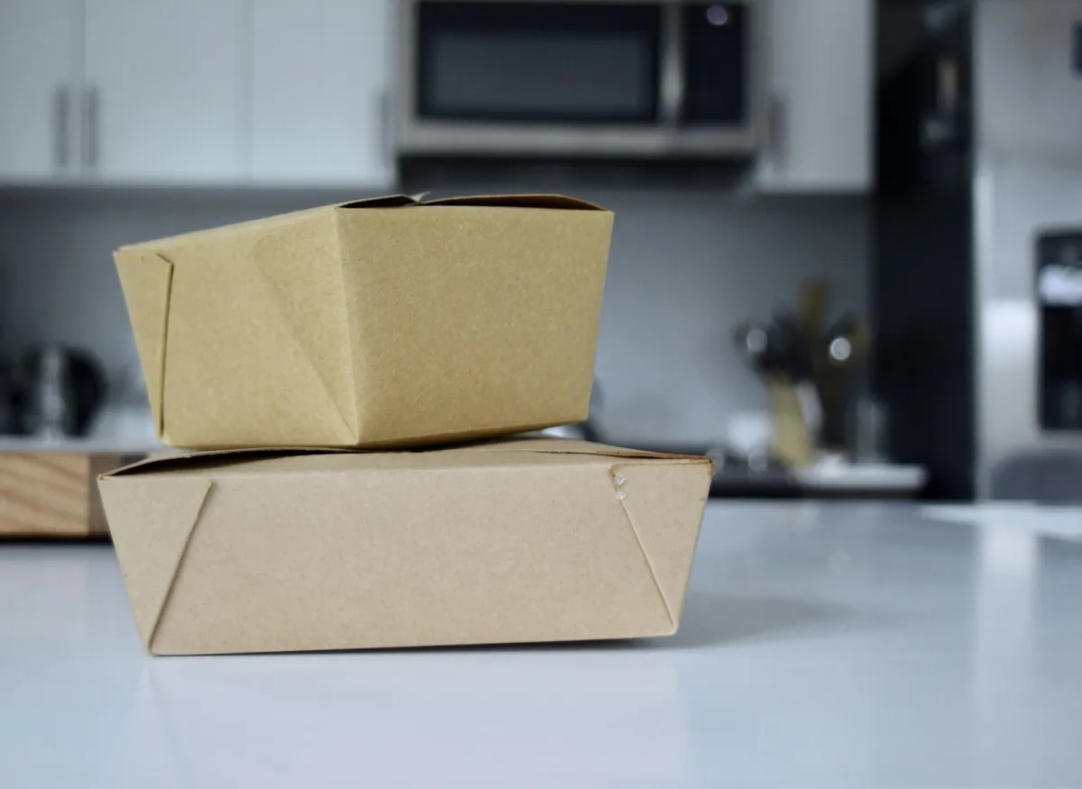 Two brown cardboard takeaway boxes stacked on a white kitchen counter