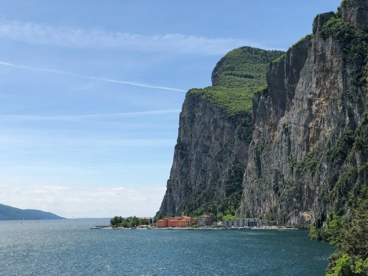 Steep green cliffs rising above the blue water of Lake Garda in Italy Steep green cliffs rising above the blue water of Lake Garda in Italy