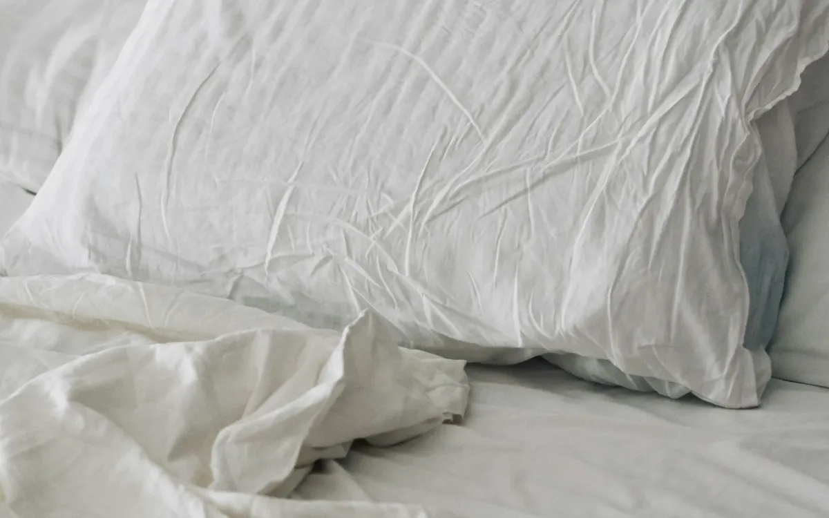 White pillow and rumpled white bedding on a bed