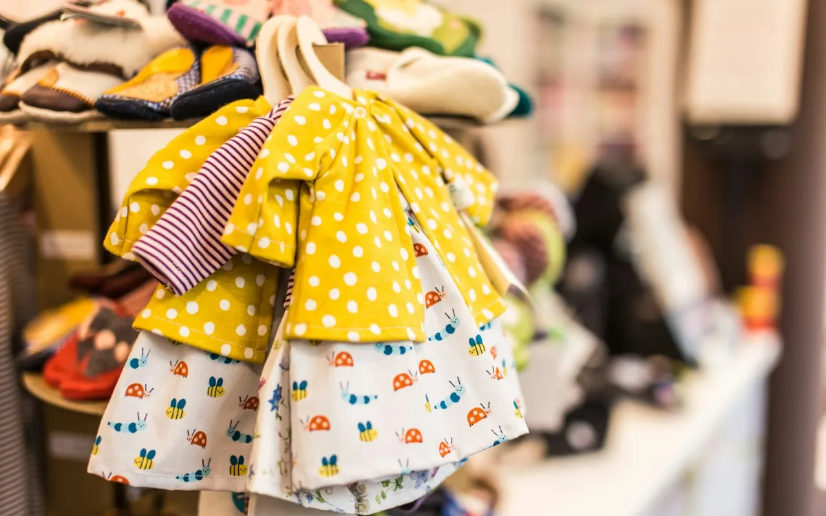Children's polka-dot and bug-print dresses on wooden hangers in a shop Children's polka-dot and bug-print dresses on wooden hangers in a shop