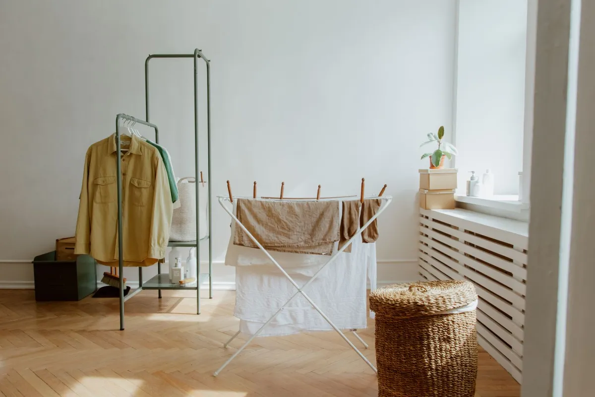 Washing drying on a folding airer in a bright room beside a radiator