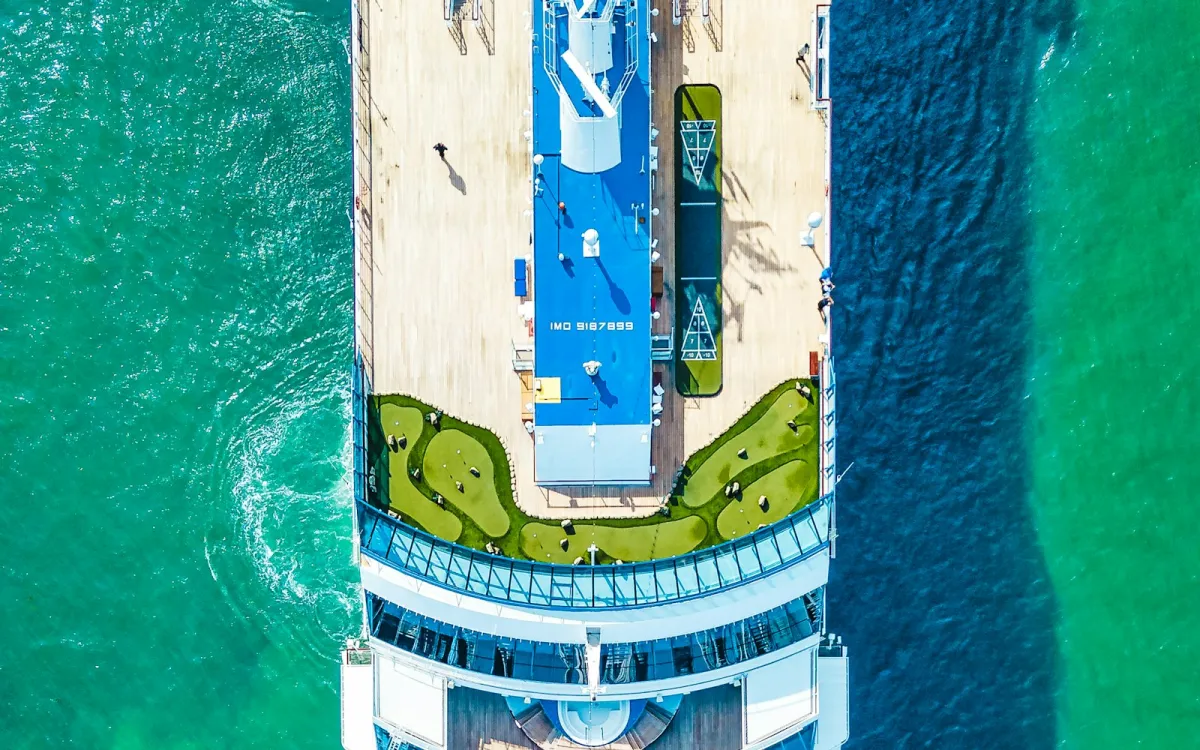 Aerial view of a cruise ship's top deck and mini golf course on turquoise sea