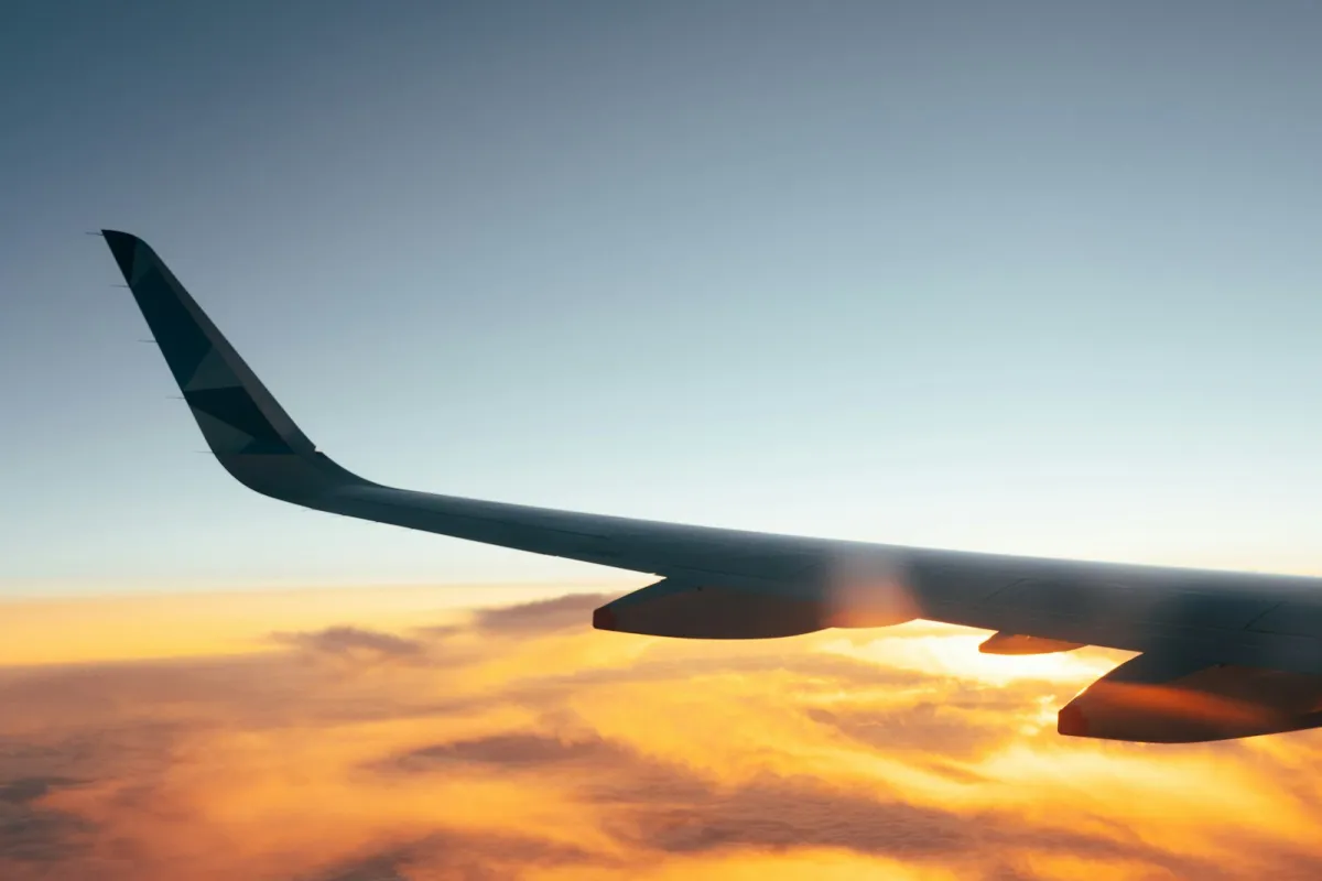 Aeroplane wing above a sea of golden clouds at sunrise
