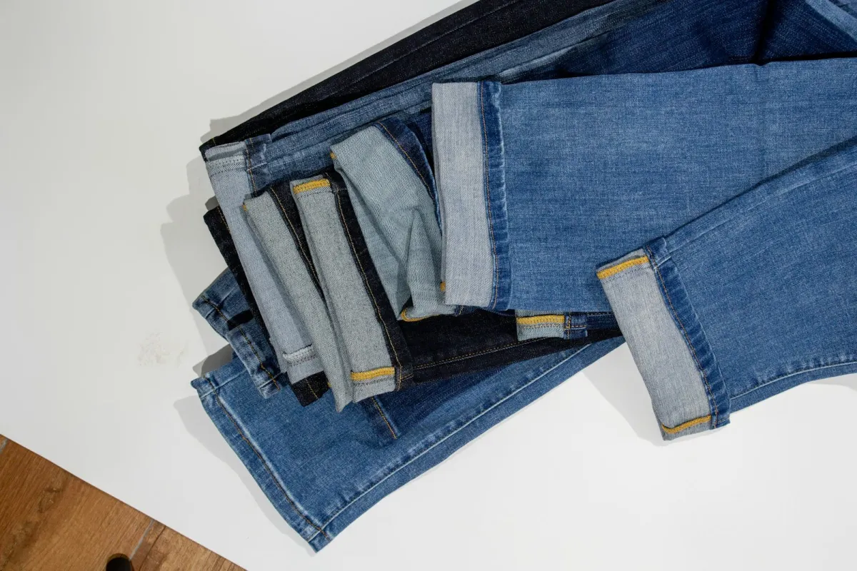 A stack of folded blue denim jeans with turned-up hems on a white surface A stack of folded blue denim jeans with turned-up hems on a white surface