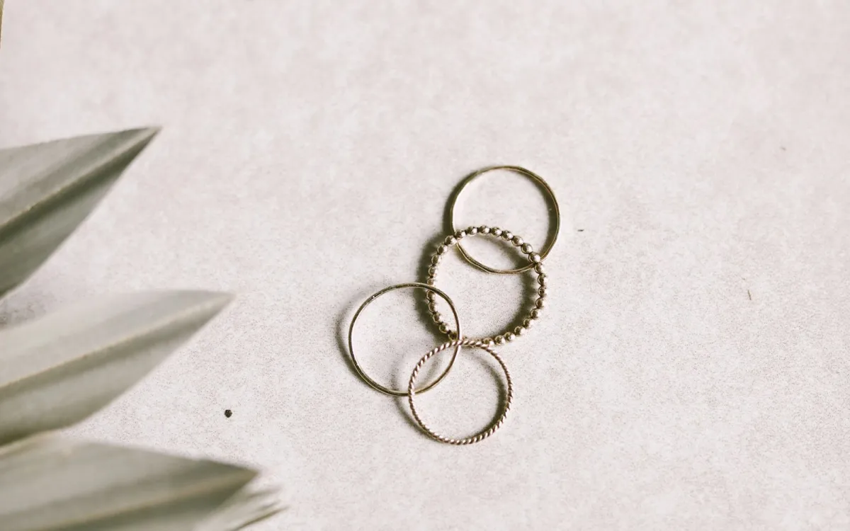 Four thin stacking rings on a pale stone surface beside dried palm leaves Four thin stacking rings on a pale stone surface beside dried palm leaves