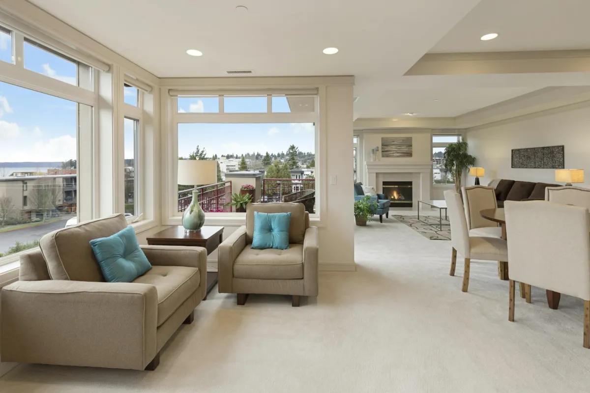 A bright, tidy open-plan living room with beige armchairs, a dining table and a fireplace A bright, tidy open-plan living room with beige armchairs, a dining table and a fireplace