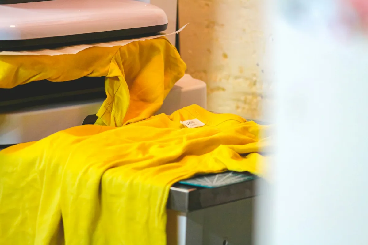 A yellow T-shirt laid on a heat press with transfer paper under the plate A yellow T-shirt laid on a heat press with transfer paper under the plate