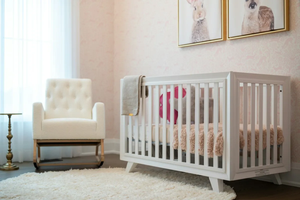 A bright nursery with a white cot, a cream rocking chair and animal prints on the wall
