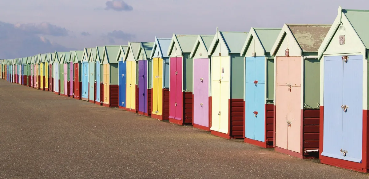 A long row of colourful beach huts along the seafront promenade in Hove A long row of colourful beach huts along the seafront promenade in Hove