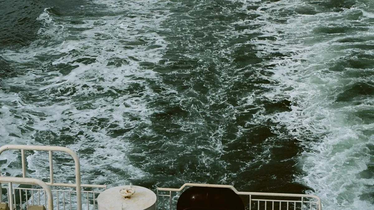 The white wake of a ferry on a choppy green sea, seen from the stern rail
