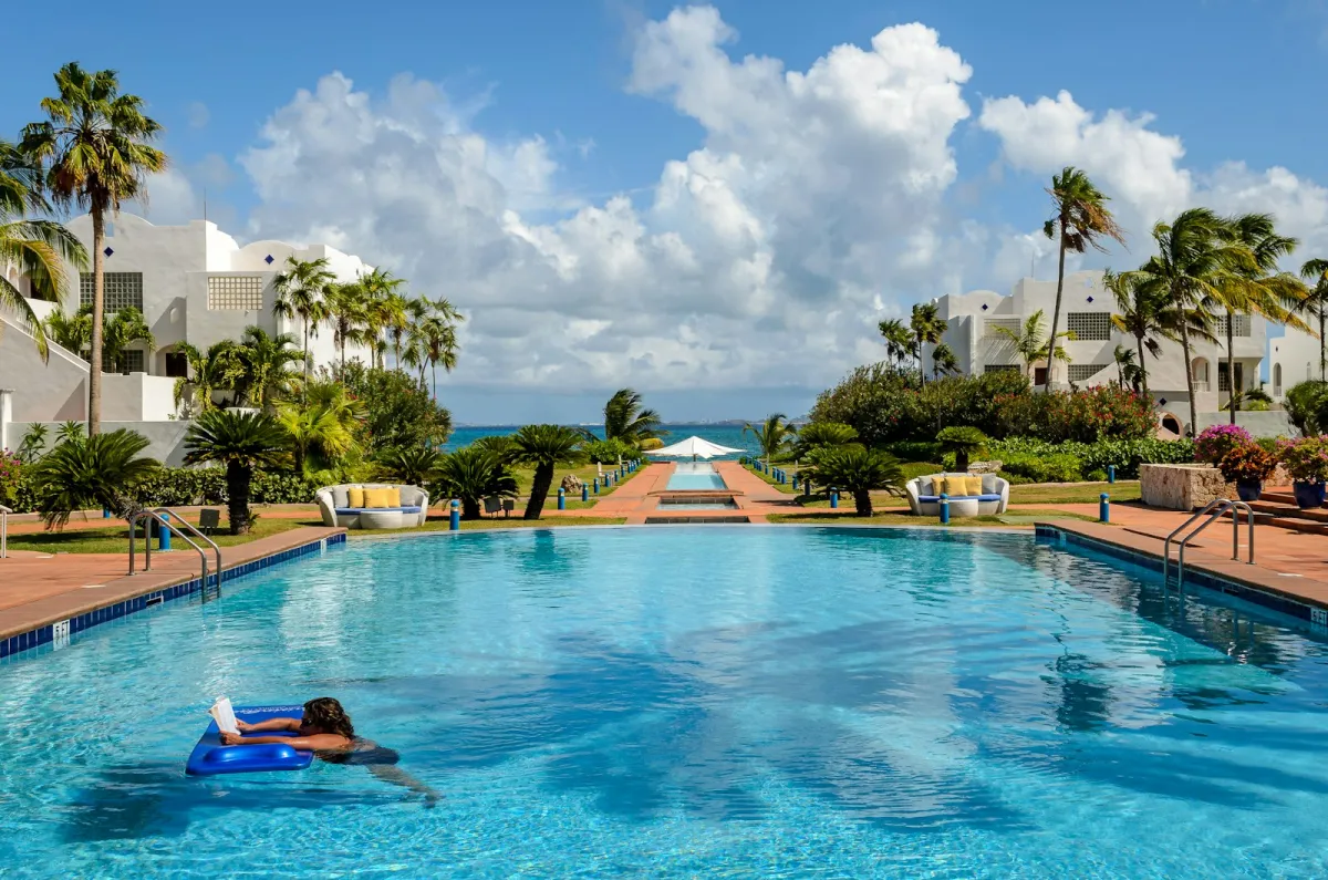 Resort swimming pool lined with palm trees under a blue sky