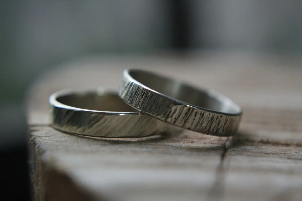 Two textured silver rings resting on a wooden block Two textured silver rings resting on a wooden block