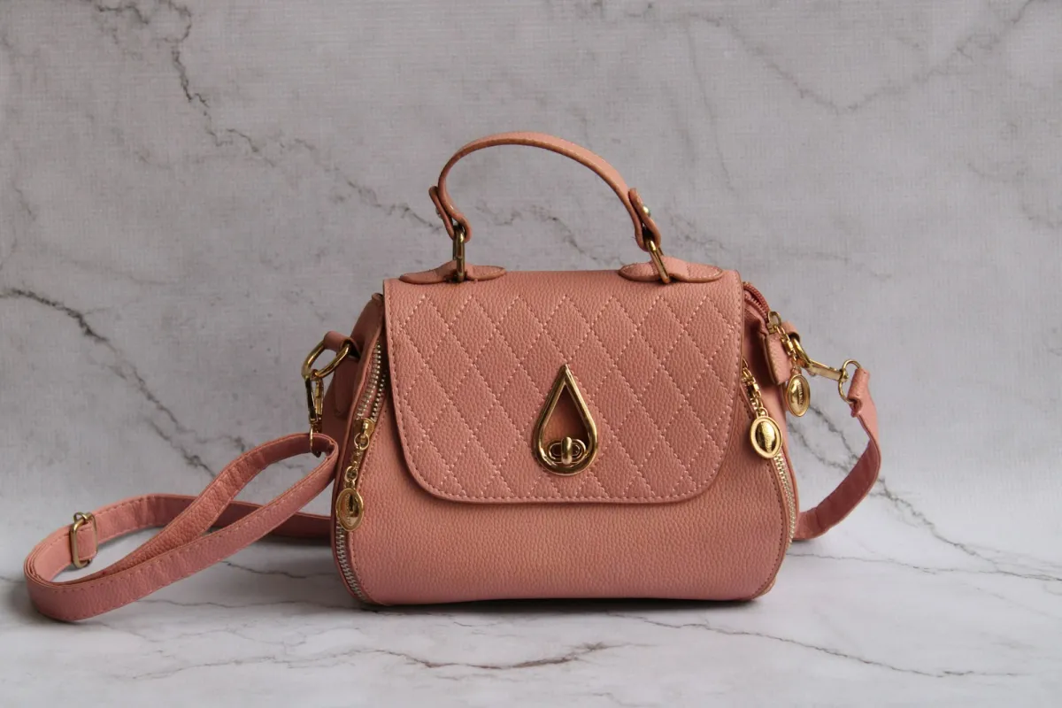 A pink quilted handbag with gold hardware on a marble surface