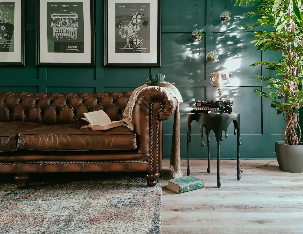 A brown leather Chesterfield sofa in a living room with books and a lamp