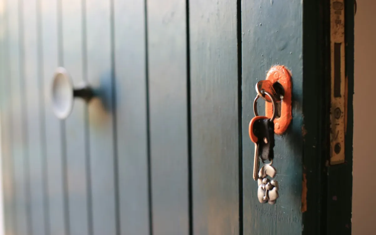 Bunch of keys hanging from the lock of a painted wooden door