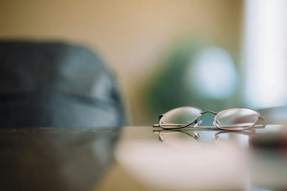 A pair of metal-framed glasses resting on a glossy table