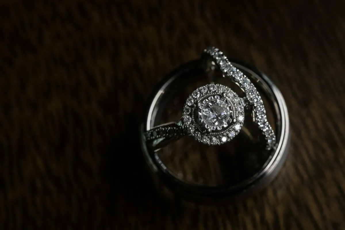 A diamond halo engagement ring and a diamond band resting inside a wedding ring