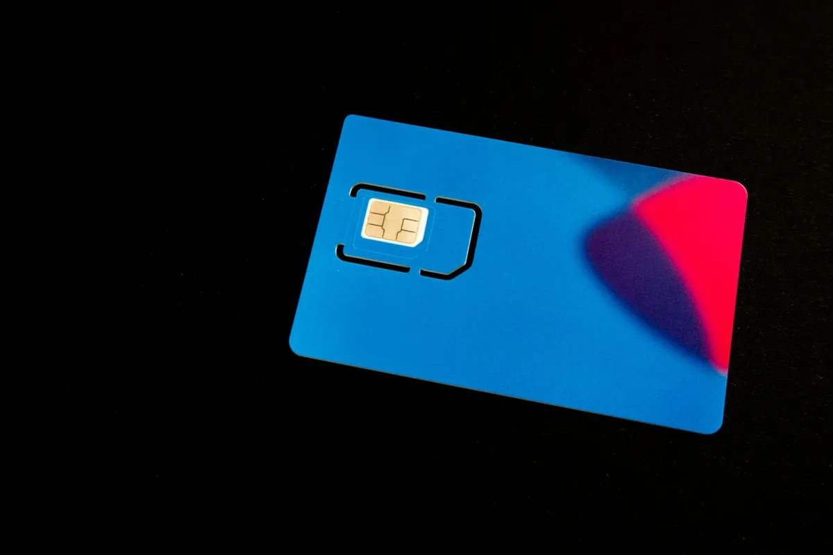 A blue SIM card holder with a gold chip on a black background A blue SIM card holder with a gold chip on a black background