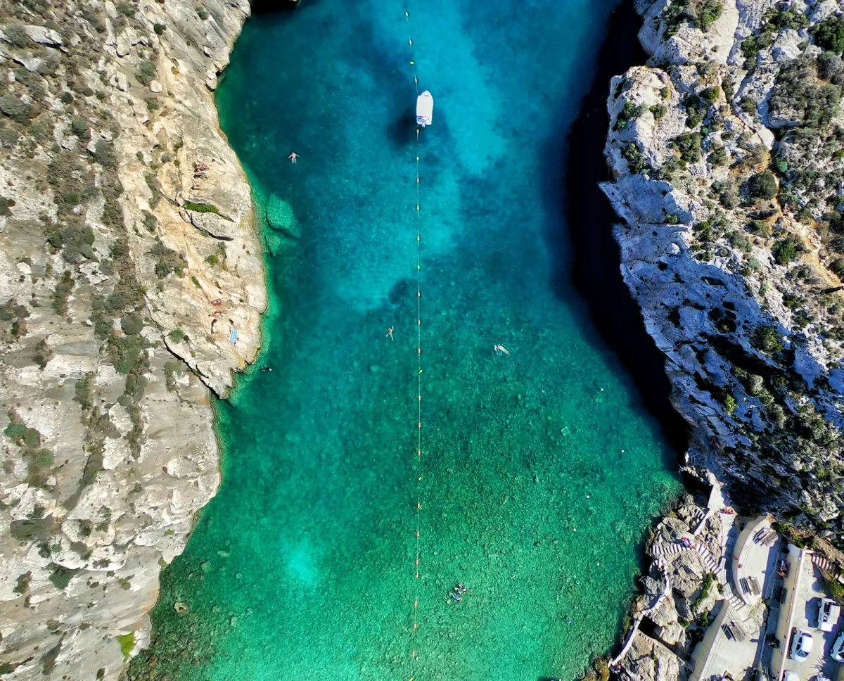 Aerial view of green water surrounded by rock formations on the coast of Gozo, Malta
