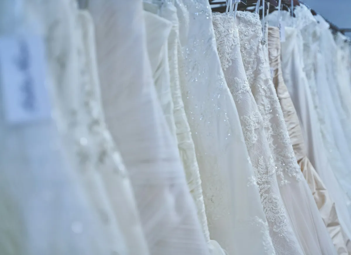 A row of white lace wedding dresses hanging on a rail A row of white lace wedding dresses hanging on a rail